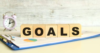 Tahta küpler, gri arka planda mali tabloların olduğu bir klasörde yatıyor. Küpler 