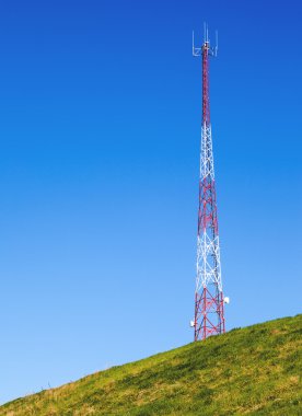 Uzun boylu iletişim kule mavi gökyüzü ile bir tepe üzerinde