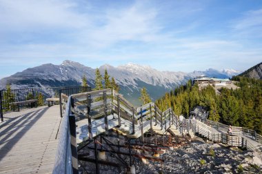 BANFF, CANADA - 2 Temmuz 2014: Ziyaretçiler, Banff Ulusal Parkı Kanada Kayalıkları 'ndaki dağ sırasının panoramik manzarası için Gondola zirvesi ile Sanson Tepesi arasındaki Sülfür Dağı' nın tepesindeki tahta kaldırımda yürüyorlar.