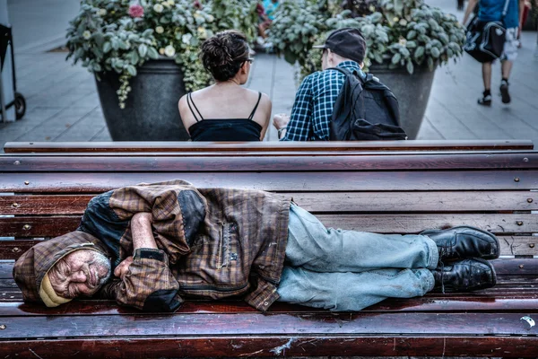 Sem-teto homem sênior dormindo no banco do parque — Fotografia de Stock