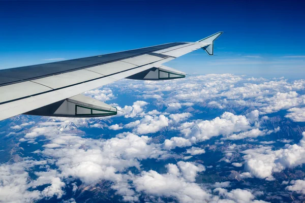 Vista de nubes y montañas rocosas fuera de la ventana del avión — Foto de Stock