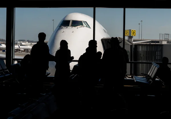 Silhouet van passagiers hun vlucht wacht — Stockfoto