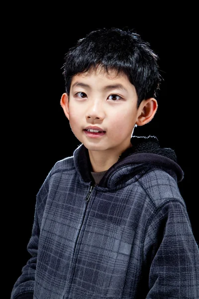 Симпатичный азиатский мальчик позирует на черном фоне в студии — стоковое фото