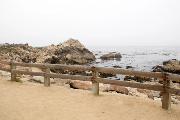 Fence on rocky sea shore — Stock Photo, Image