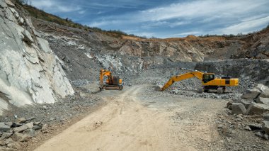 Çukur taşı ocağında ağır makineler (kazıcı, hidrolik çekiç).