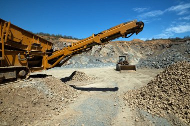 Güneşli bir günde taş ocağında taş öğütücü ve buldozer..