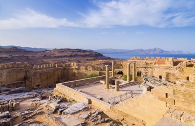 Athena Lindia 'dan Doris Temple' ın panoramik görüntüsü, Acropolis of Lindos 'taki ortaçağ şatosu altında mavi körfez, Rhodes Adası