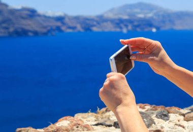 Santorini 'nin cep telefonu kullanan güzel bir kadının arka plan görüntüsü..