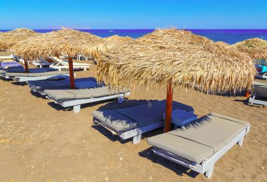 Satorini, Yunanistan ve Avrupa 'da saman şemsiyeleri ve tahta güneşliklerle dolu kumsal