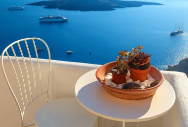 Oia, Santorini, Cyclades, Yunanistan 'da denize bakan terasta çiçeklerle süslenmiş bir masa.