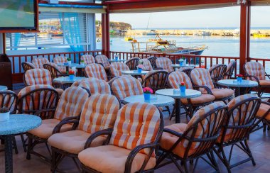 Tables and chairs at a waterfront bar with views across the harbour, Hersonissos, Crete, Greece