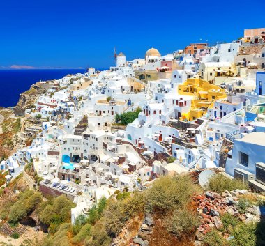 Ege Denizi 'ndeki geleneksel Yunan ada mimarisinin Oia köyünün nefes kesici manzarası ve öğlen güneşinin yansıması. Santorini Adası, Yunanistan, Avrupa.