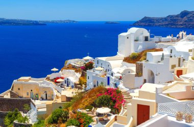 Yunanistan 'ın Santorini adasındaki Oia kasabası. Caldera, Ege denizi üzerinde mavi kubbeleri olan geleneksel ve ünlü evler ve kiliseler