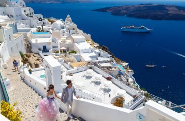 SANTORINI, GREECE - 22 HAZİRAN 2017: Mutlu Asyalı gelin ve damat birbirlerine bakıyorlar ve Santorini adasının caddesinde el ele tutuşuyorlar.