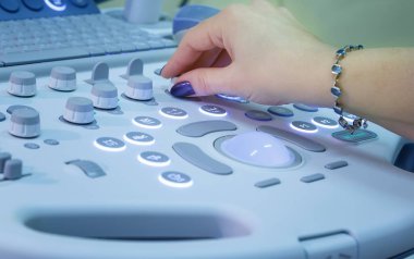 Klinikte ultrason cihazı kullanan uzman bir doktor.