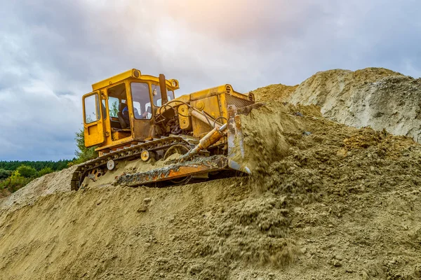 Bulldozer blade close-up of a worker working with sand on a construction site.