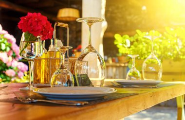 Akdeniz usulü terasta yemek için restoran masası hazırlandı çatal bıçak, şarap kadehleri ve baharatlarla.