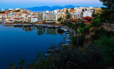 Güzel güneydeki Agios Nikolaos kasabası yaz akşamları. Akşam ışıklarıyla rıhtımdaki Voulismeni gölünün suyunda kayıklar sallanıyor. Girit Adası. Yunanistan
