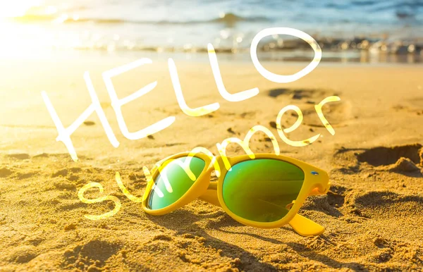 여름에는 모래가 해변에서 노란색 선글라스를 씁니다 배경에 자기장의 흐릿하게 보인다 — 스톡 사진