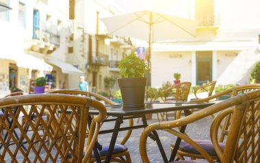 Sunny City of Chania 'nın arka planında, masanın ortasında bir çiçek olan çömlek. Turistler, Girit Yunanistan. Alan derinliği, bulanıklık. Yunan Sokak Kafesi.