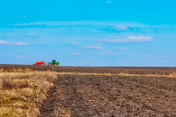 Tractor sowing seeds in plowed field spring time — Stock Photo, Image