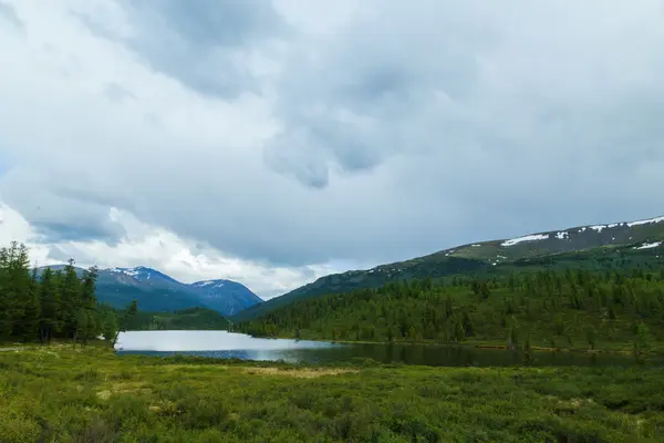 Fjällsjö i bakgrunden av glaciärer och dyster sky — Stockfoto