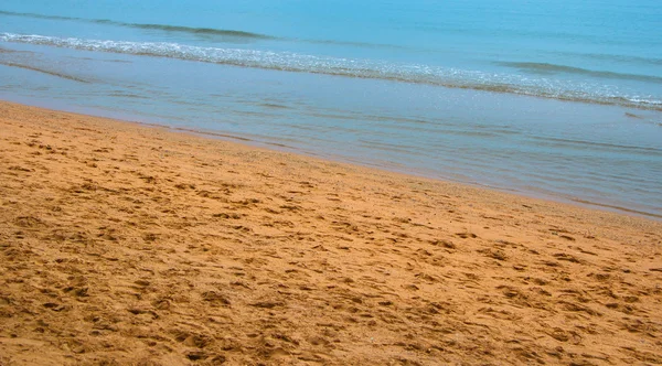 Spiaggia costiera con tracce di gambe e un mare calmo — Foto Stock