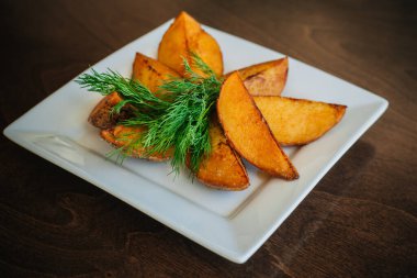 Otlu fırında patates dilimleri. Altın kabuklu. Fast food.