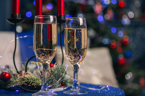 Два бокала с шампанским на праздничном столе. На фоне новогодних украшений.