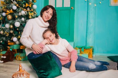 Anne ve kızı Noel kapısının yanındaki merdivenlerde oturmuş yeni yılı bekliyorlar. Sevgi dolu bir aile Noel ağacını keser ve hediye verir. Manzarada sekiz yaşında bir kadın ve kız.