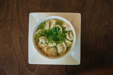 Etli hamur köfteleri ve siyah arka planda beyaz tabakta otlar. Rus halk mutfağı.