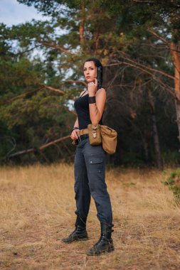 Doğasında tabanca olan bir kız. Sarı otların arka planına karşı. Kadın ordusu ava çıktı. Sıcak bir ülkede askeri harekat