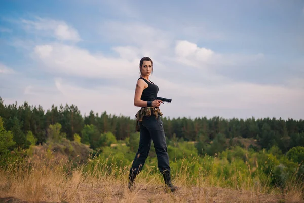 那是个带着手枪的女孩在黄草的背景下 猎杀中的女兵炎热国家的军事行动 — 图库照片