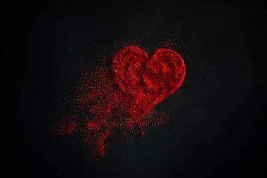 Scattered red heart made of sparkles on a black background. Shimmering dust symbol. Broken love concept clipart
