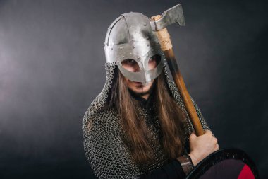 Viking gri bir arka planda baltayla duruyor. Zincirli zırhlı ve kasklı bir adam silahını sallıyor. Zırhlı bir ortaçağ savaşçısı savaşa girer..