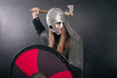 Viking gri bir arka planda baltayla duruyor. Zincirli zırhlı ve kasklı bir adam silahını sallıyor. Zırhlı bir ortaçağ savaşçısı savaşa girer..