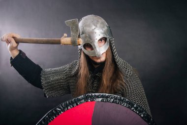 Viking gri bir arka planda baltayla duruyor. Zincirli zırhlı ve kasklı bir adam silahını sallıyor. Zırhlı bir ortaçağ savaşçısı savaşa girer..