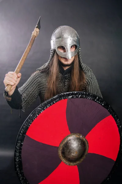 Viking gri bir arka planda baltayla duruyor. Zincirli zırhlı ve kasklı bir adam silahını sallıyor. Zırhlı bir ortaçağ savaşçısı savaşa girer..