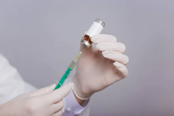 Close-up hands are taking medicine into a syringe from an ampoule. Viruses fly in the air. Vaccination and immunization of the population