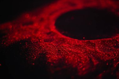 Pullardan yapılmış kırmızı güneş. Siyah arka planda dağınık pullar. Uzay dokusu. Parlayan kum