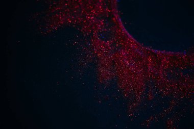 Pullardan yapılmış kırmızı güneş. Siyah arka planda dağınık pullar. Uzay dokusu. Parlayan kum