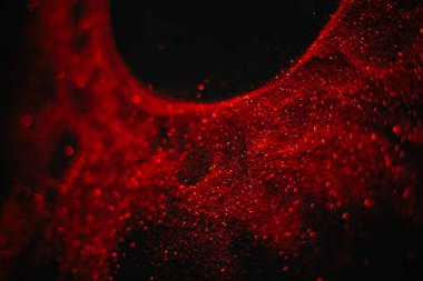 Pullardan yapılmış kırmızı güneş. Siyah arka planda dağınık pullar. Uzay dokusu. Parlayan kum