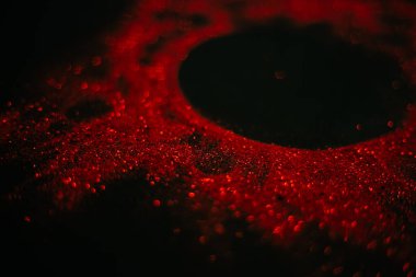 Pullardan yapılmış kırmızı güneş. Siyah arka planda dağınık pullar. Uzay dokusu. Parlayan kum