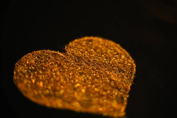 心の黄金の砂のスパンコールから作られた 黒の背景にスパンコール 金の質感 — ストック写真