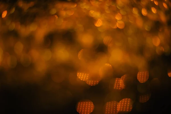 Gold sand from sequins. Scattered sparkles on a black background. Blurred bokeh background — Stock Photo, Image