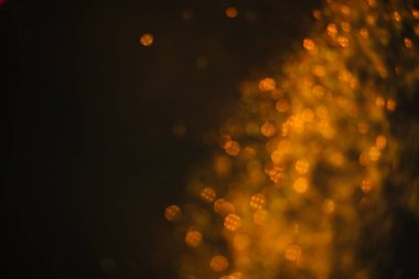 Pullardan altın kum. Siyah arka plana yayılmış ışıltılar. Bulanık bokeh arkaplanı
