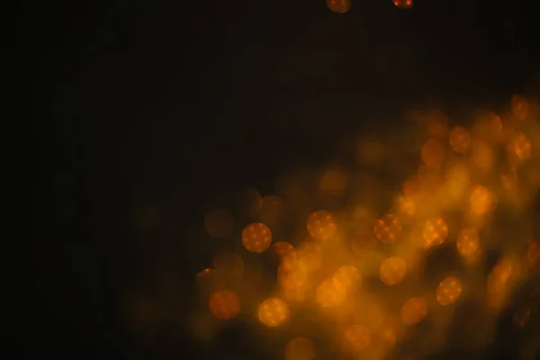 Gold sand from sequins. Scattered sparkles on a black background. Blurred bokeh background — Stock Photo, Image