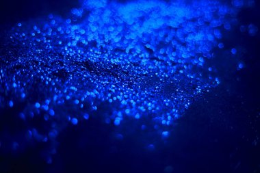 Mavi parıltılı doku. Siyah arka planda serpiştirilmiş tohumlar. Işıldayan etki. Bokeh. Bulanık arkaplan