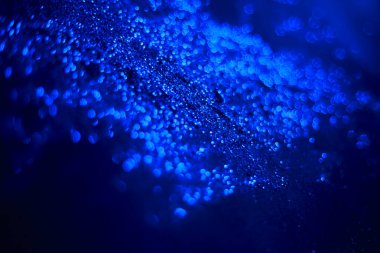 Mavi parıltılı doku. Siyah arka planda serpiştirilmiş tohumlar. Işıldayan etki. Bokeh. Bulanık arkaplan