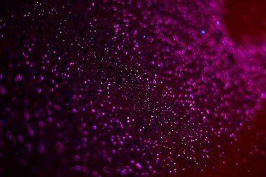 Mor parıltı dokusu. Tohumlar siyah arka plana saçılmış. Işıldayan etki. Bokeh. Bulanık arkaplan